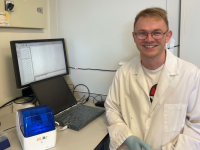Tom Bird sitting by computer in lab coat