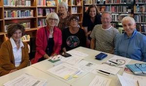 The Friends of HOPE Foundation are gathered around a table at the library/