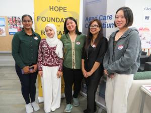 Five HOPE scholars standing in front of the yellow HOPE banner