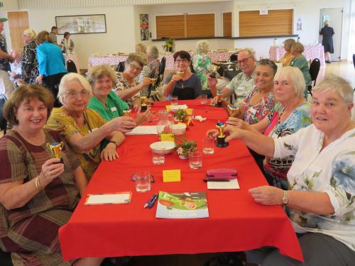 10 people around a table with red cloth