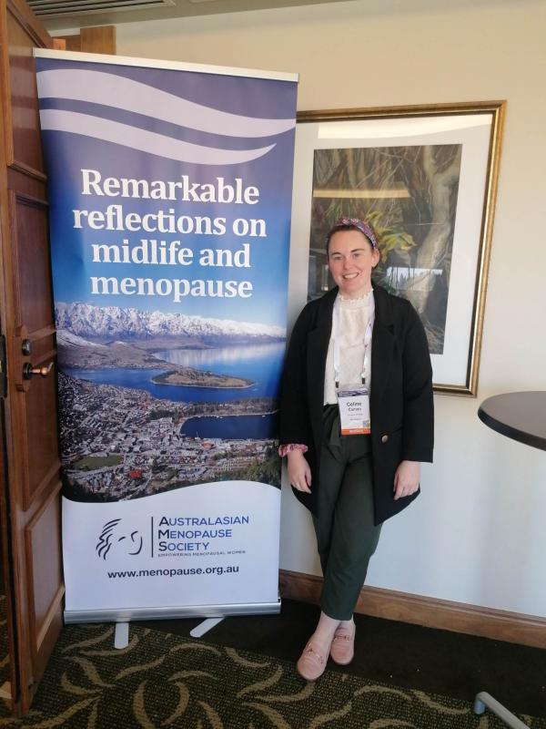 HOPE Scholar standing next to the Australasian Menopause Society banner